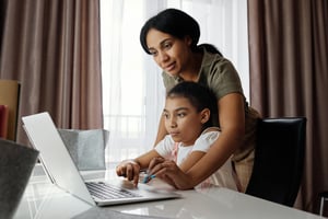 parent helping child on laptop