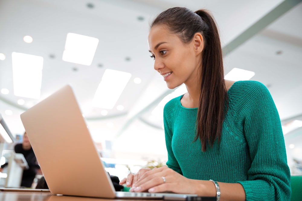 Portrait of a happy female student using laptop computer in university-1